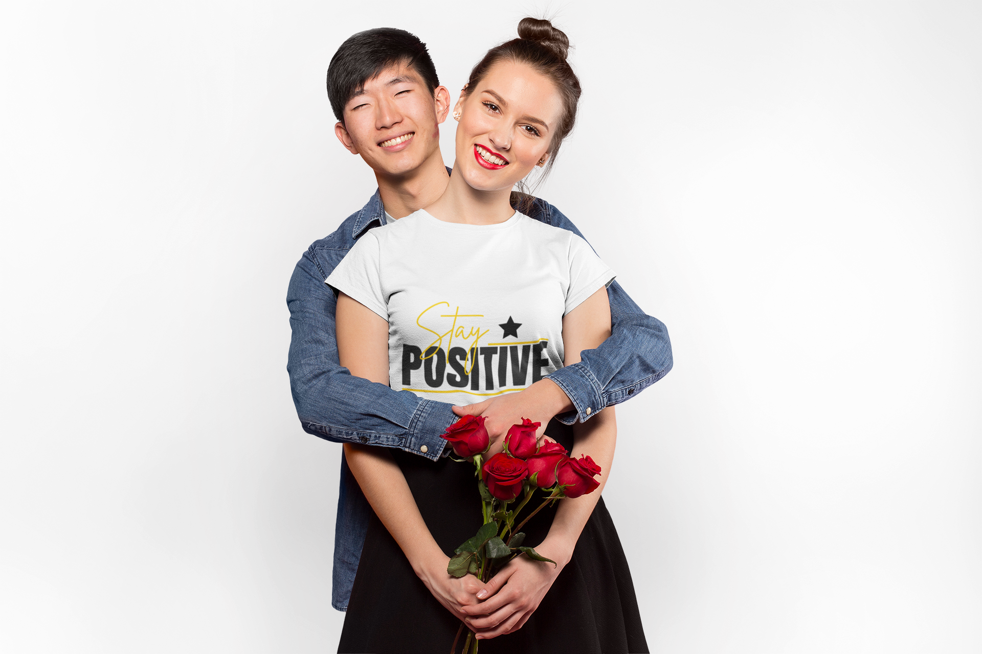 Two people hugging, one holding red roses, against a white background
