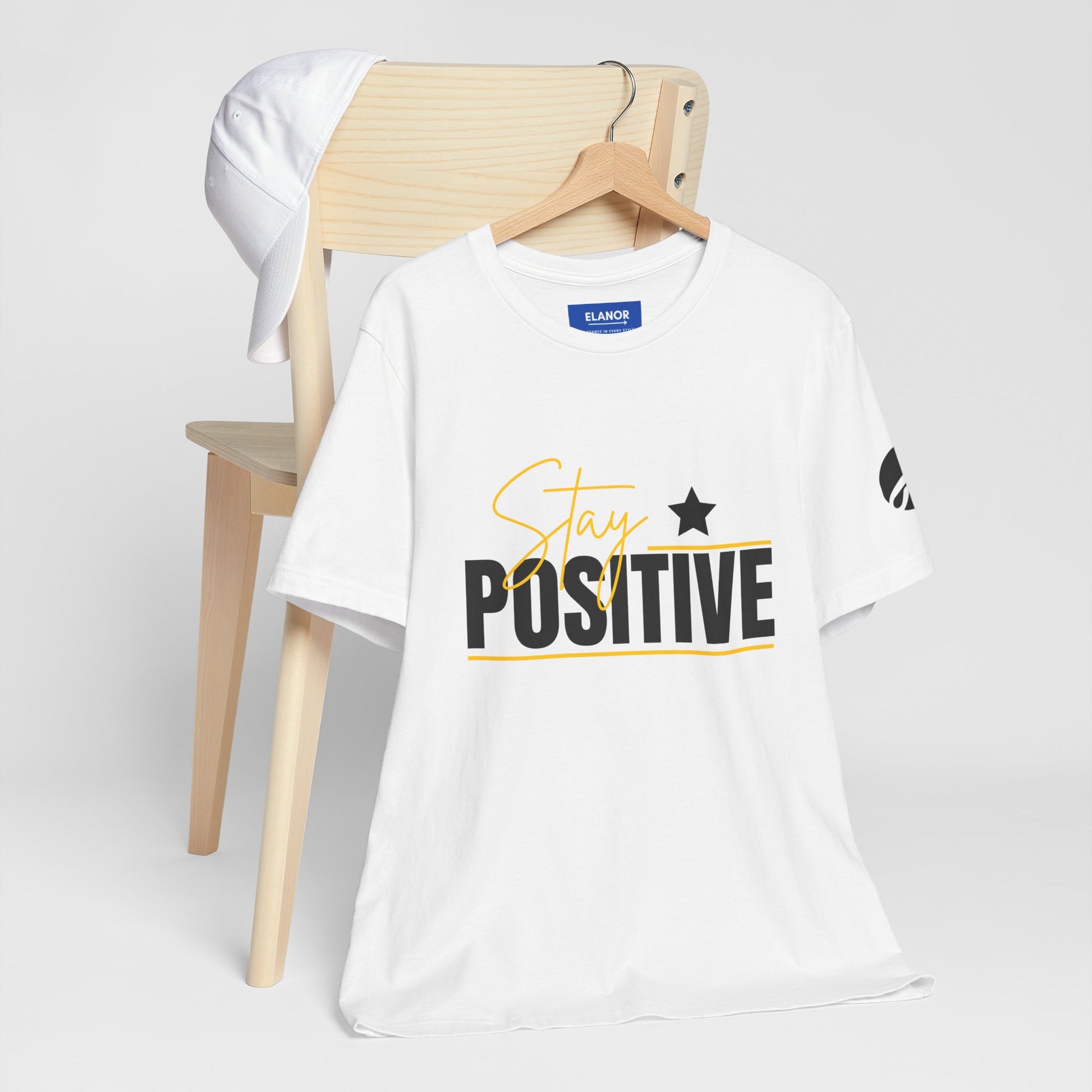 White t-shirt with 'Stay Positive' text on a wooden chair against a white background